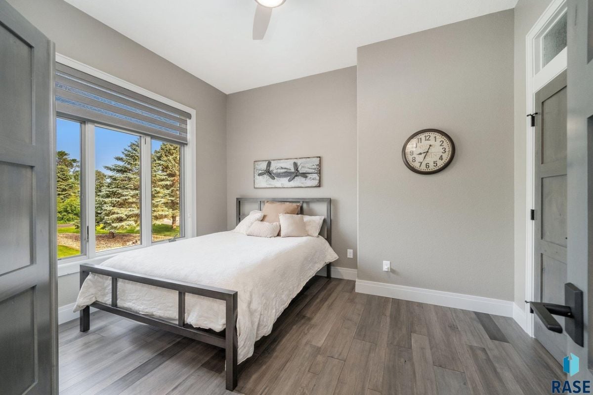 Bedroom with wood flooring, ceiling fan and glass windows.