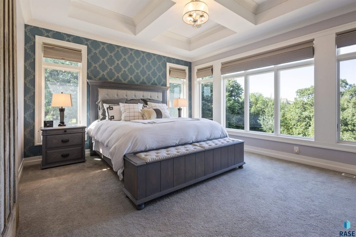 Bedroom with carpet flooring, a large bed and large glass windows.
