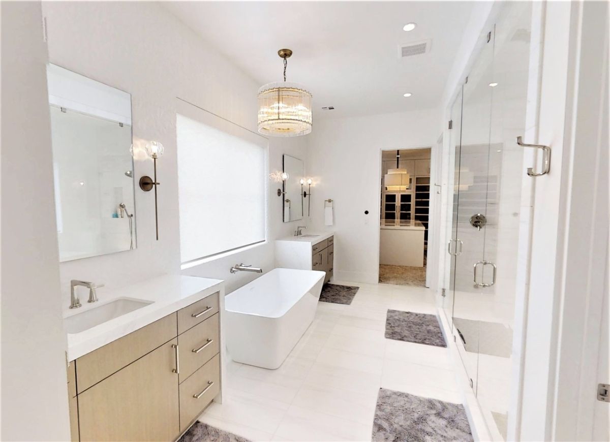 Bathroom with custom lighting, sinks and a bath tub.