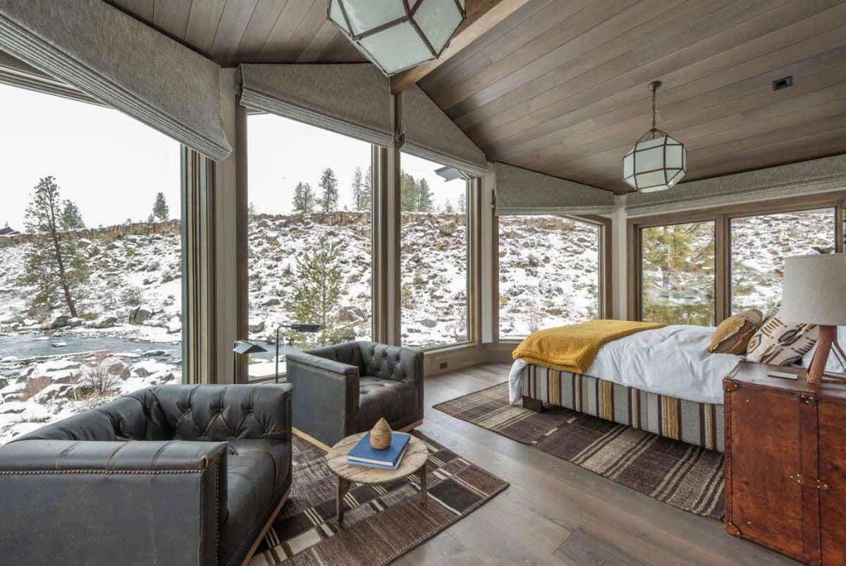 Bedroom with couches and large glass windows overlooking the river.