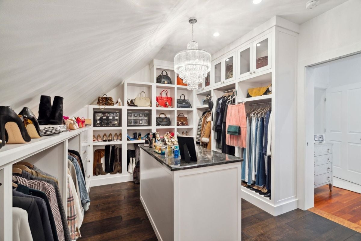 Walk-in closet with white shelves and a chandelier.
