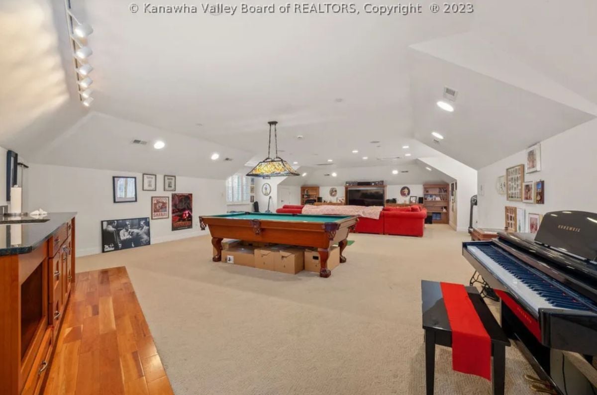Recreation room with billiard table, a piano, couches and a TV.