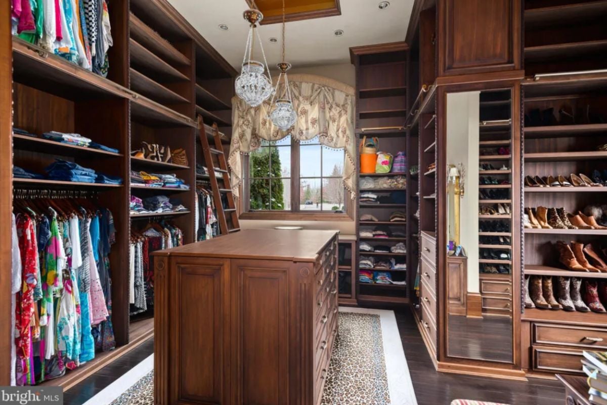 Walk-in closet with wooden shelves and wood flooring.