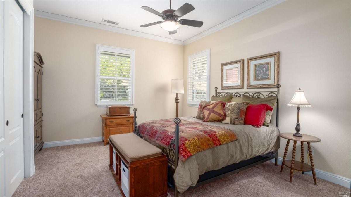 Bedroom with carpet flooring, a ceiling fan, and a large bed.
