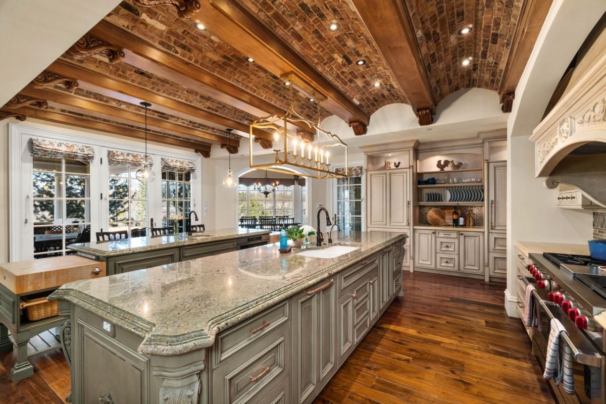 Kitchen with a large island, wood flooring, custom lighting, and wooden beams.