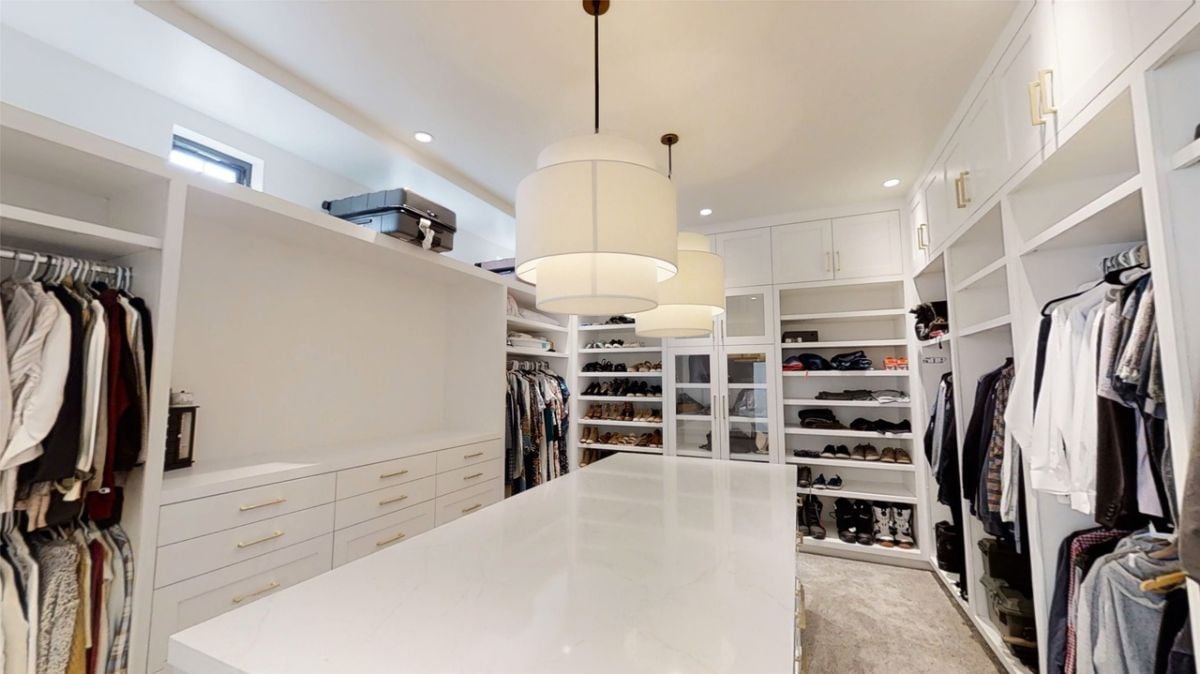 Walk-in closet with white cabinets and drawers.