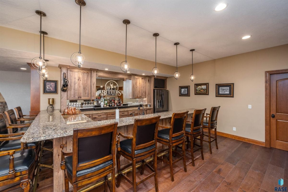 Bar with custom lighting, granite countertops and chairs.