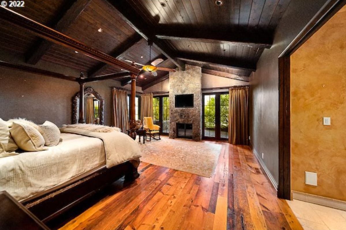 Bedroom with open beam ceiling, wood flooring and a fireplace.