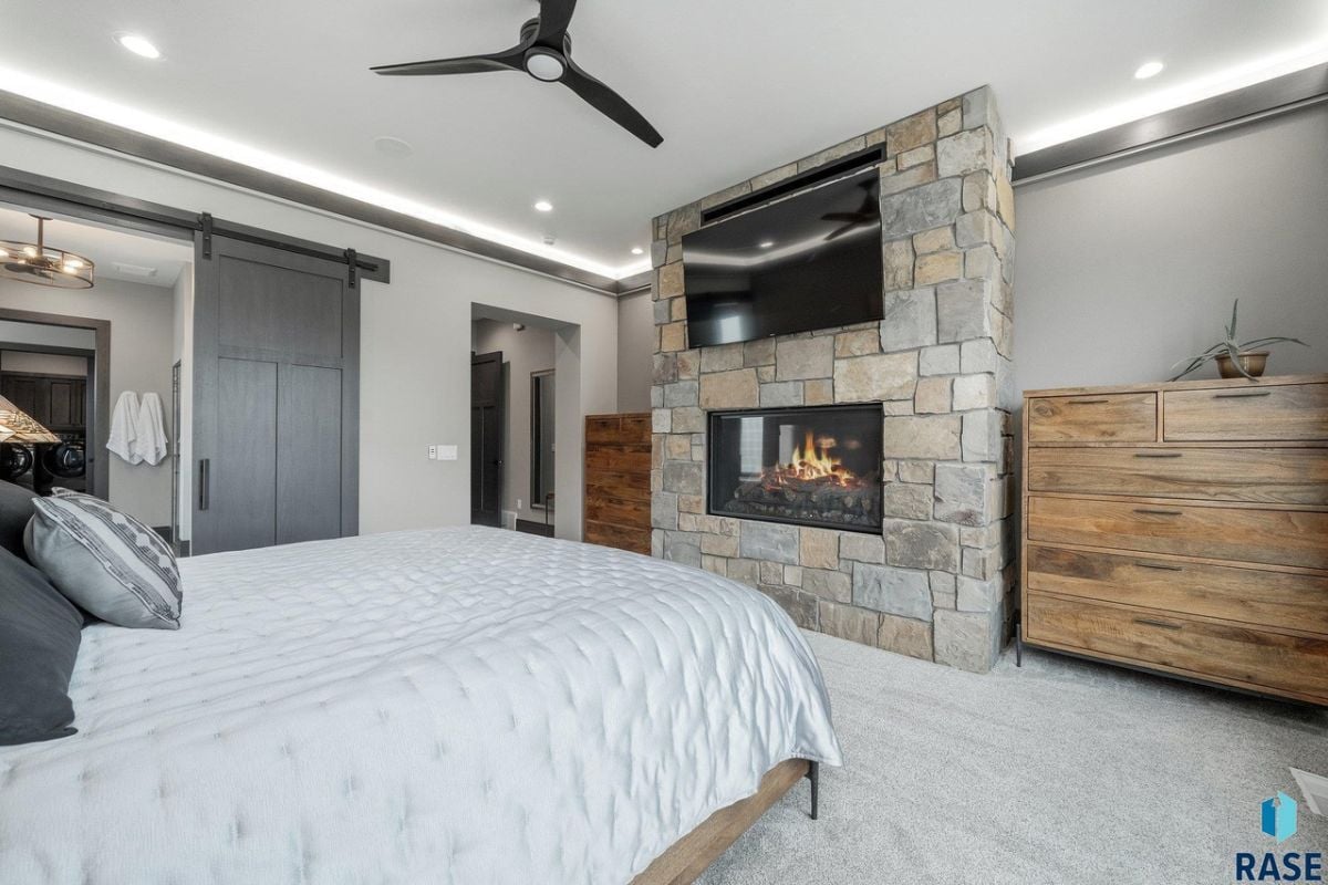 Bedroom with carpet flooring, a ceiling fan and a fireplace.