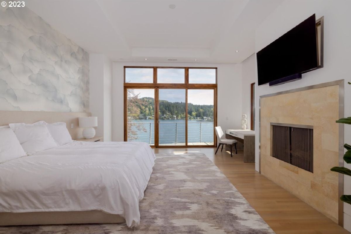 Bedroom with a TV, fireplace, glass doors and a view of the lake.