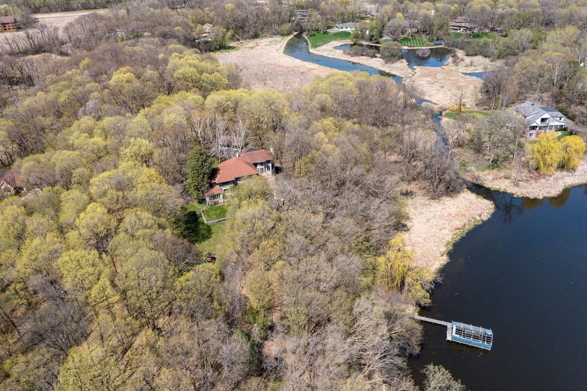 Aerial view of the property with trees and lake.