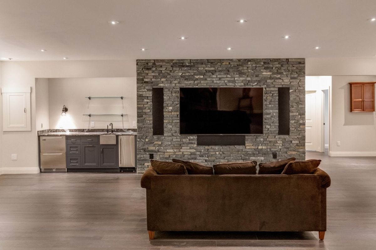Media room with a couch, custom lighting, and a large flat screen TV.