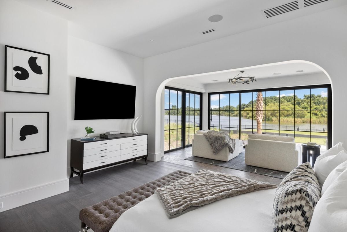 Bedroom with wood flooring, a TV, glass windows and glass doors.