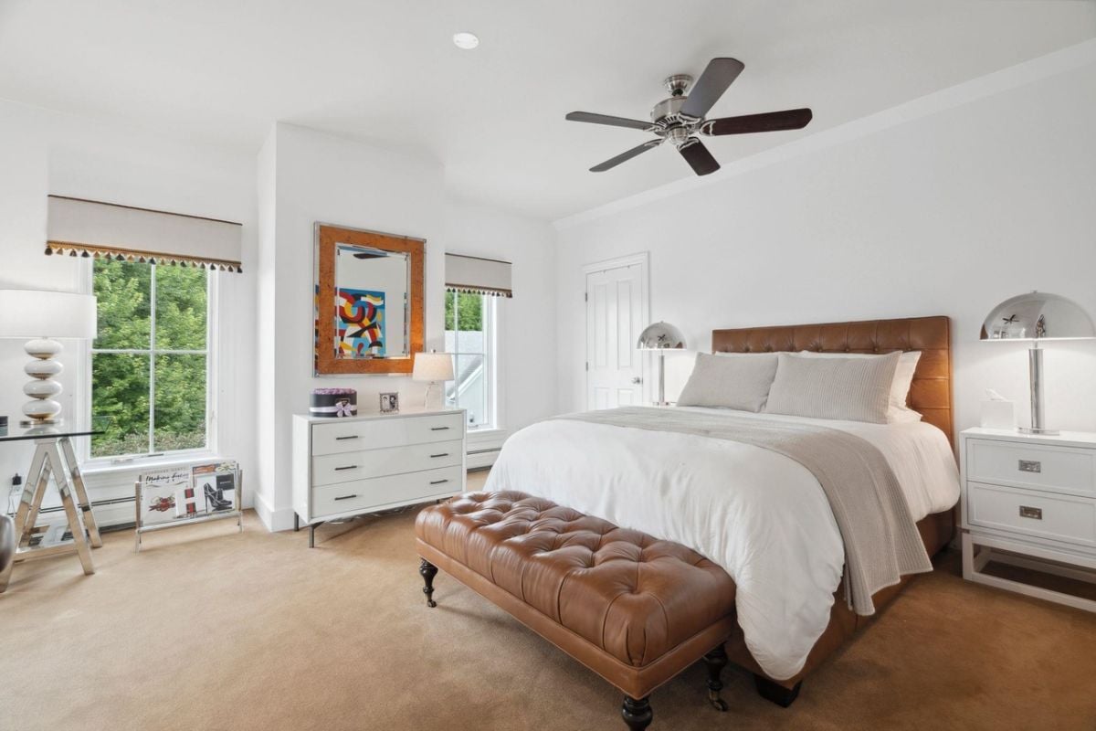 Bedroom with carpet flooring, a large bed and a ceiling fan.