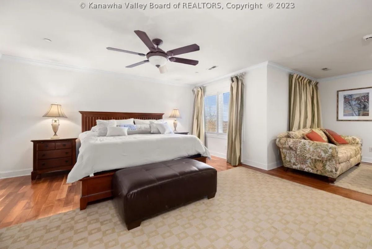 Bedroom with wood flooring, a couch and a large bed.
