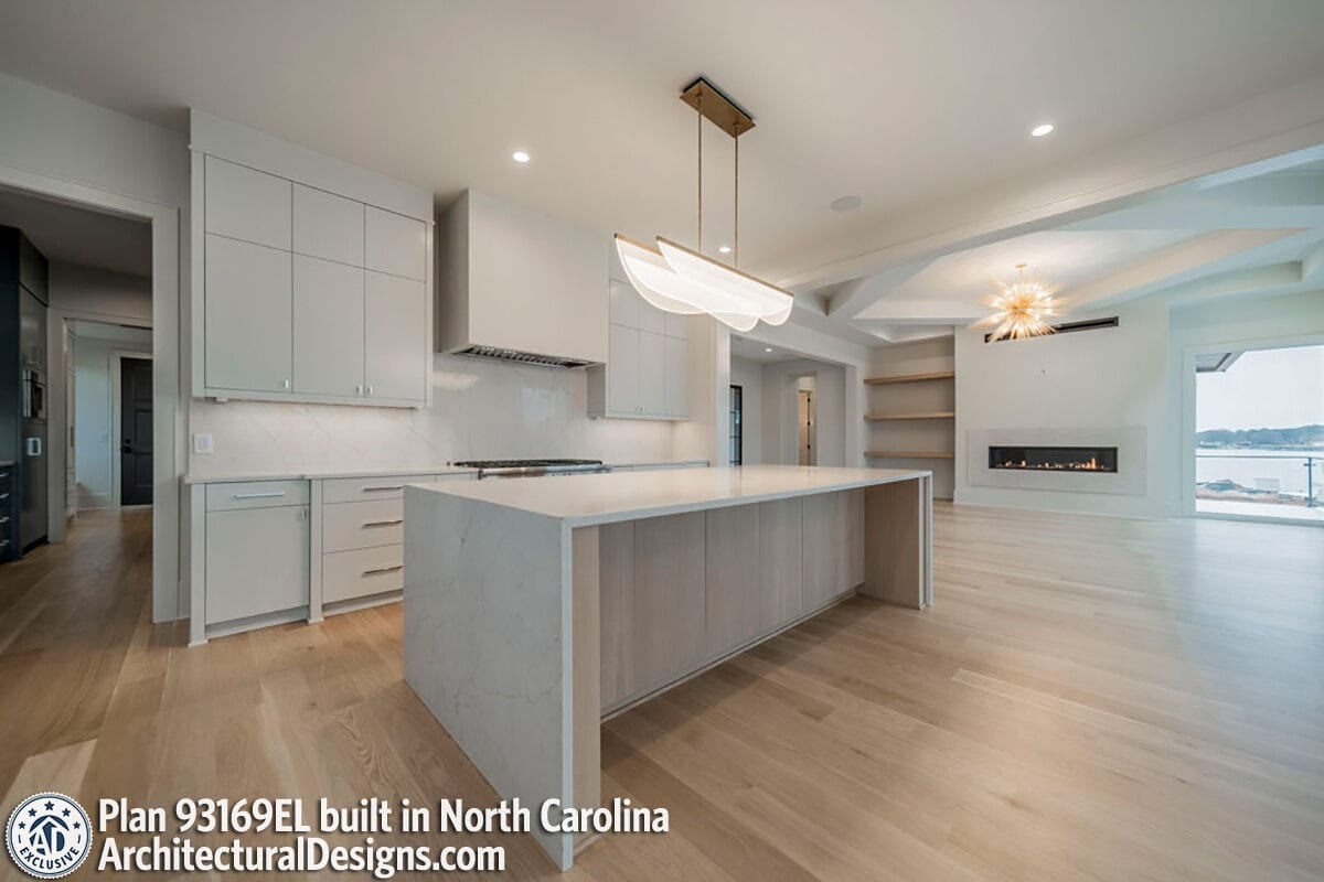 Kitchen with custom cabinetry and a waterfall island topped with a linear chandelier.