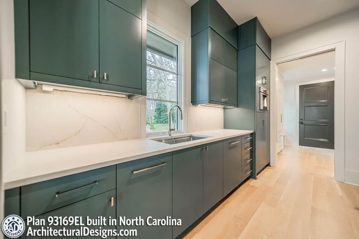 Scullery with green cabinets, a prep sink, and a marble countertop that extends to the backsplash.