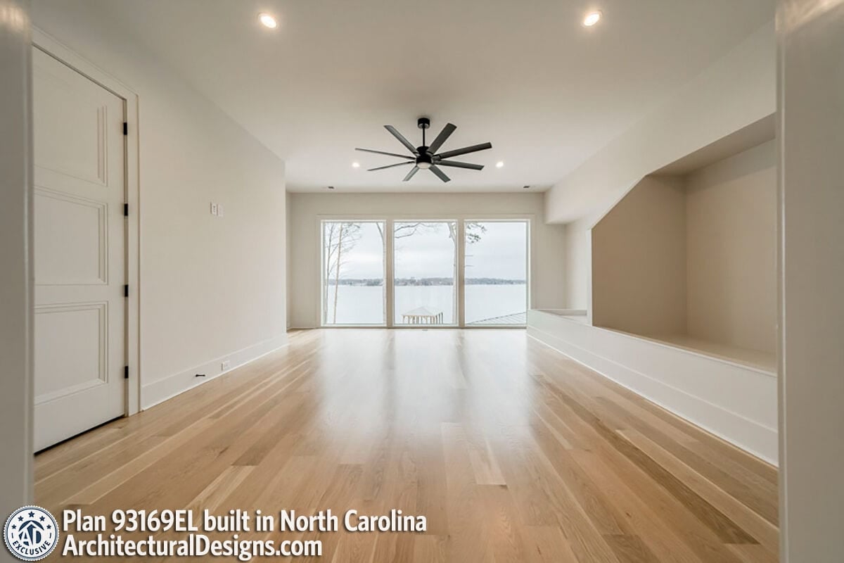 Secondary bedroom with hardwood flooring and a wall of windows overlooking the surrounding landscape.