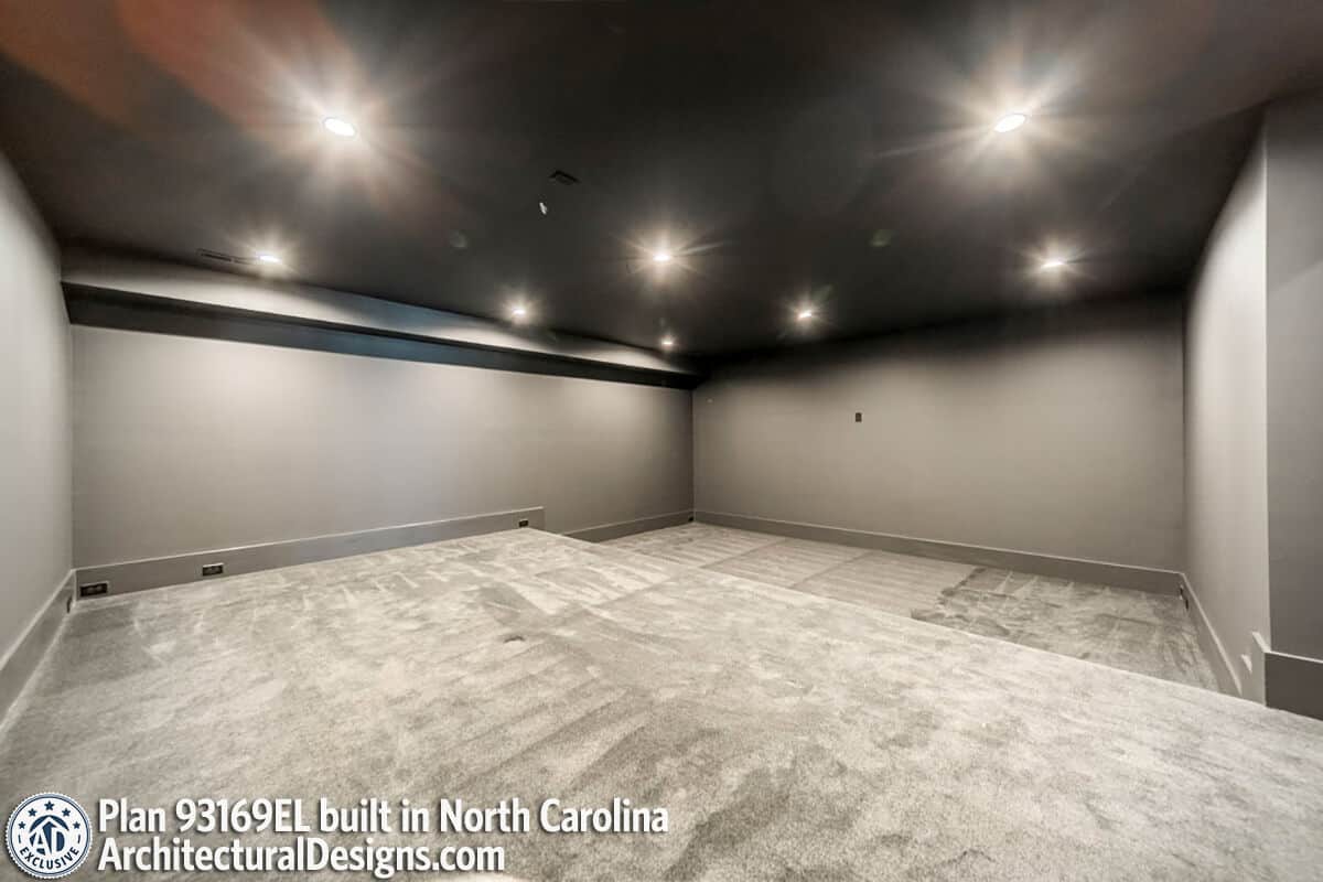 Media room with carpeted floor, gray walls, and a black regular ceiling.