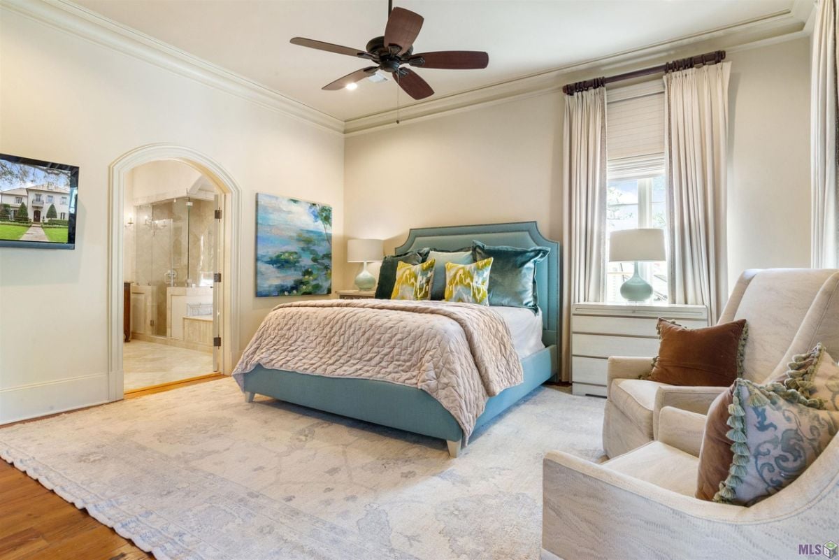 Bed in colorful sheet and a ceiling fan.