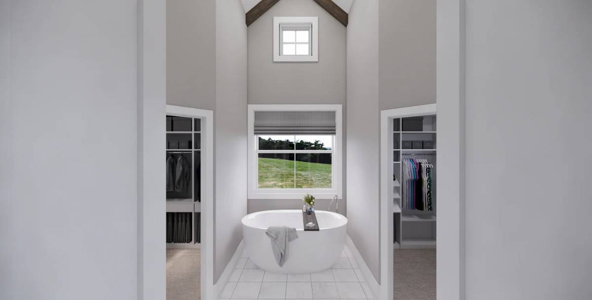 Primary bathroom with a freestanding tub flanked by his and her walk-in closets.