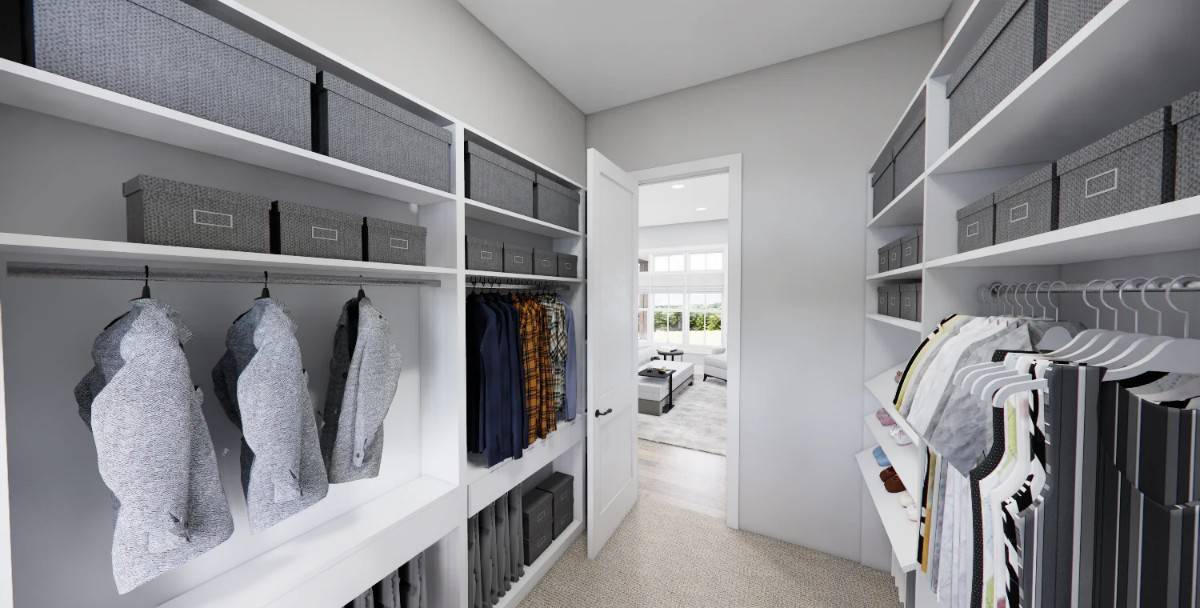 Primary walk-in closet with ample storage and a carpeted floor.