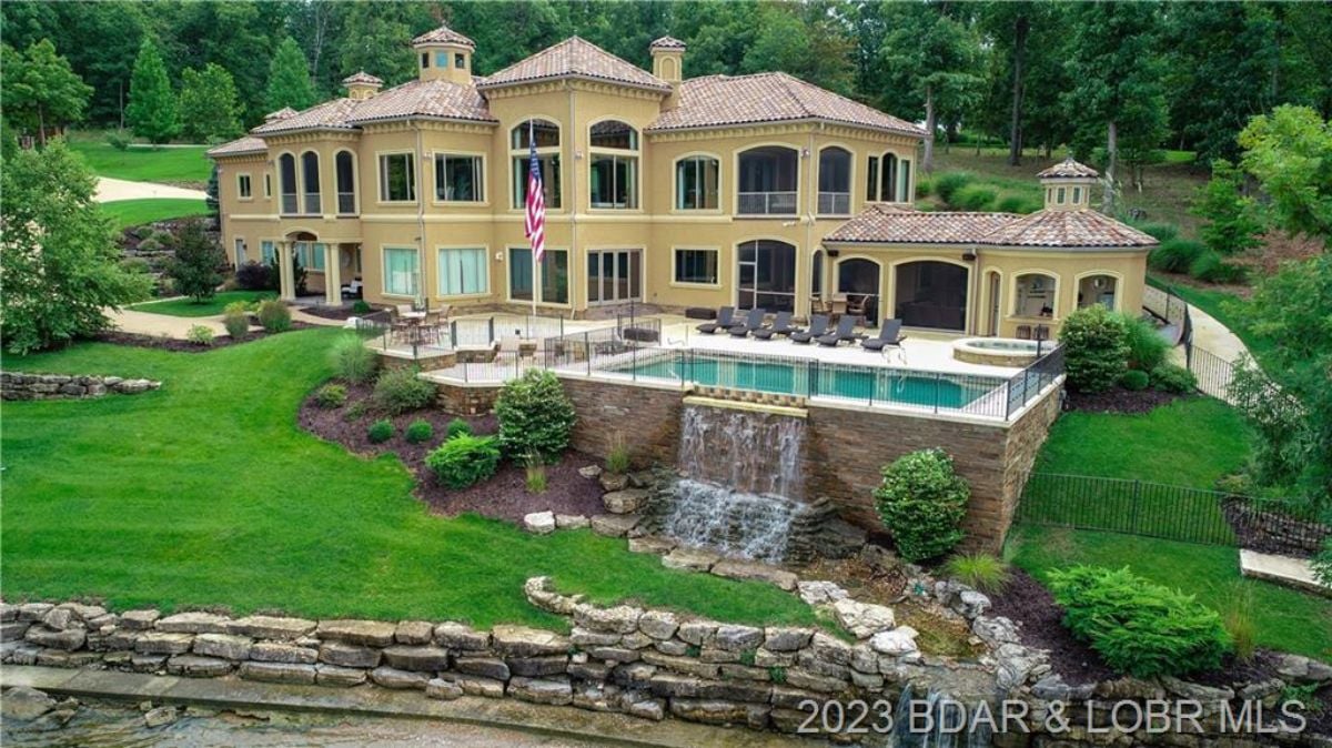 Aerial front view featuring the pool and the mansion in Muirfield Dr, Porto Cima, MO.