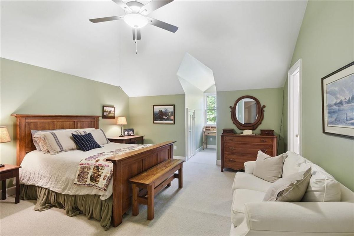 Bedroom with white couch and a mirror.