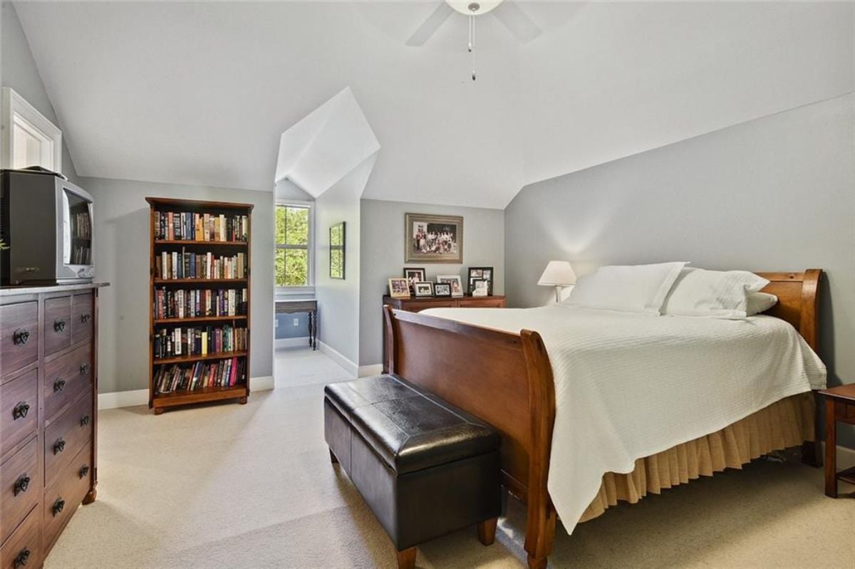 Bedroom with white sheet and a book shelf.