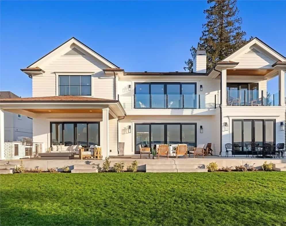 Rear view of the house showcasing its spacious outdoor living, huge windows, and balconies framed with glass railings.