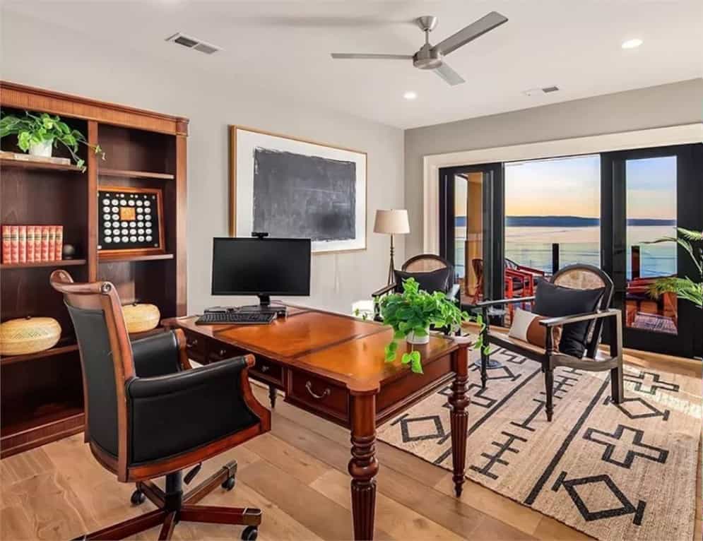Home office with a wooden desk, matching chairs, and outdoor access via glass sliders.