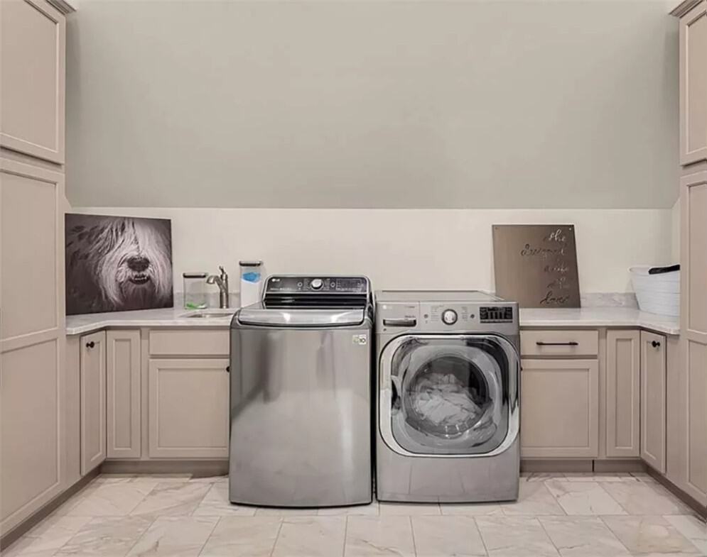 Laundry room with ample storage, quartz counter, and limestone flooring.