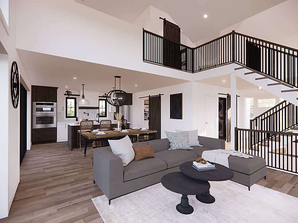 Living room and kitchen with hardwood flooring, white walls, and a two-story ceiling.