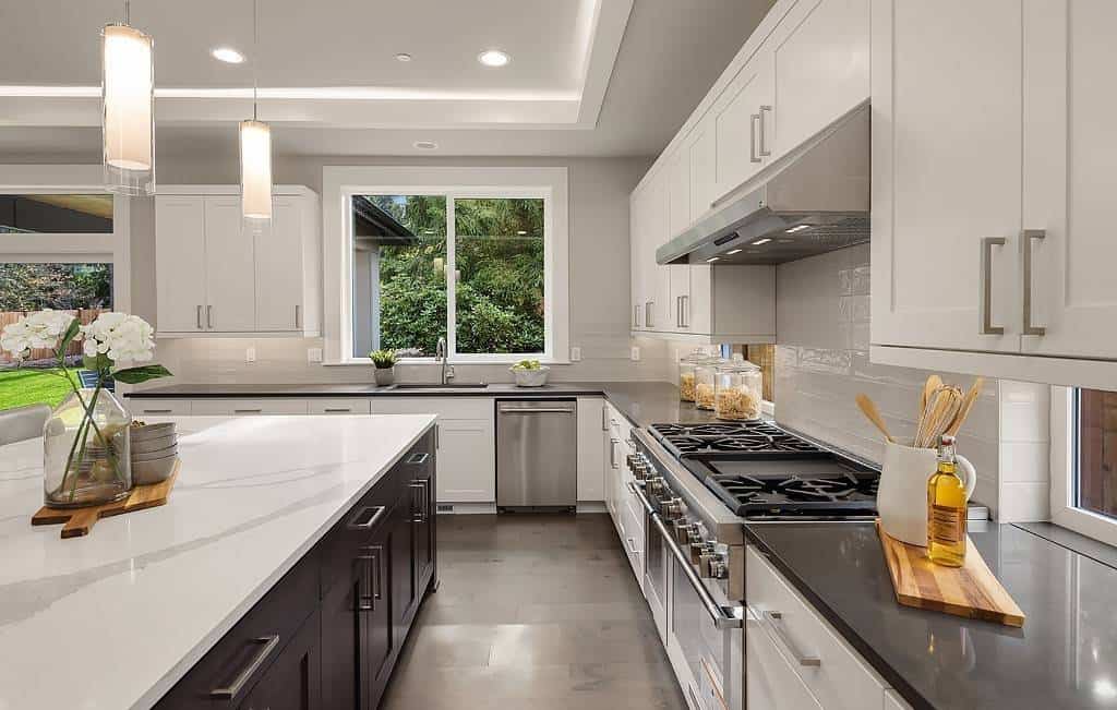 Kitchen with contrasting cabinets, a large center island, and a sink under the sliding windows.
