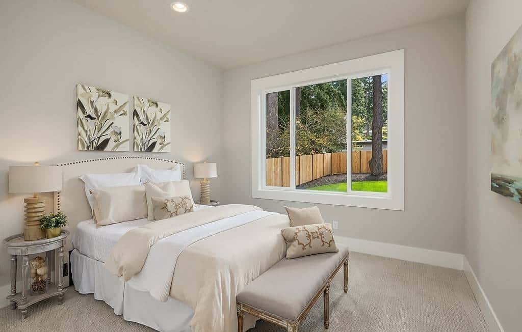 Secondary bedroom with round nightstands and an upholstered bed complemented with a cushioned bench.