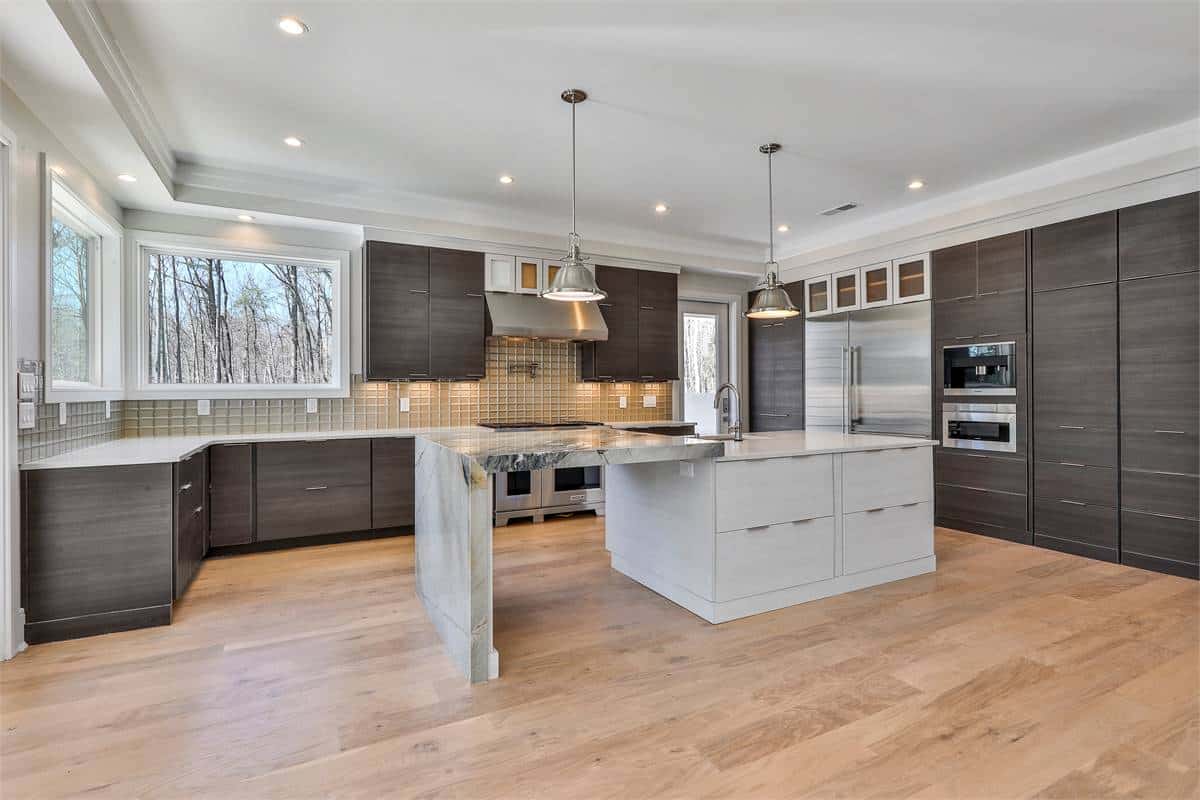Kitchen with dark wood cabinets, premium appliances, and a center island integrated with a marble eating bar.