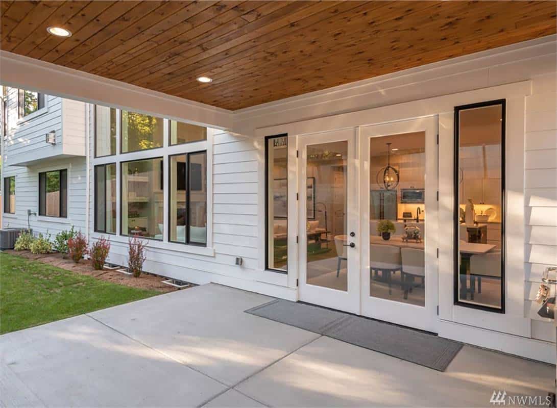 Rear patio with sliding glass doors, wood-paneled ceiling, and a concrete floor.