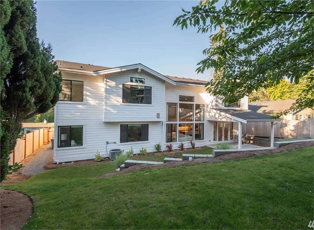 Rear view of the house with horizontal siding, sliding windows, and a covered patio.