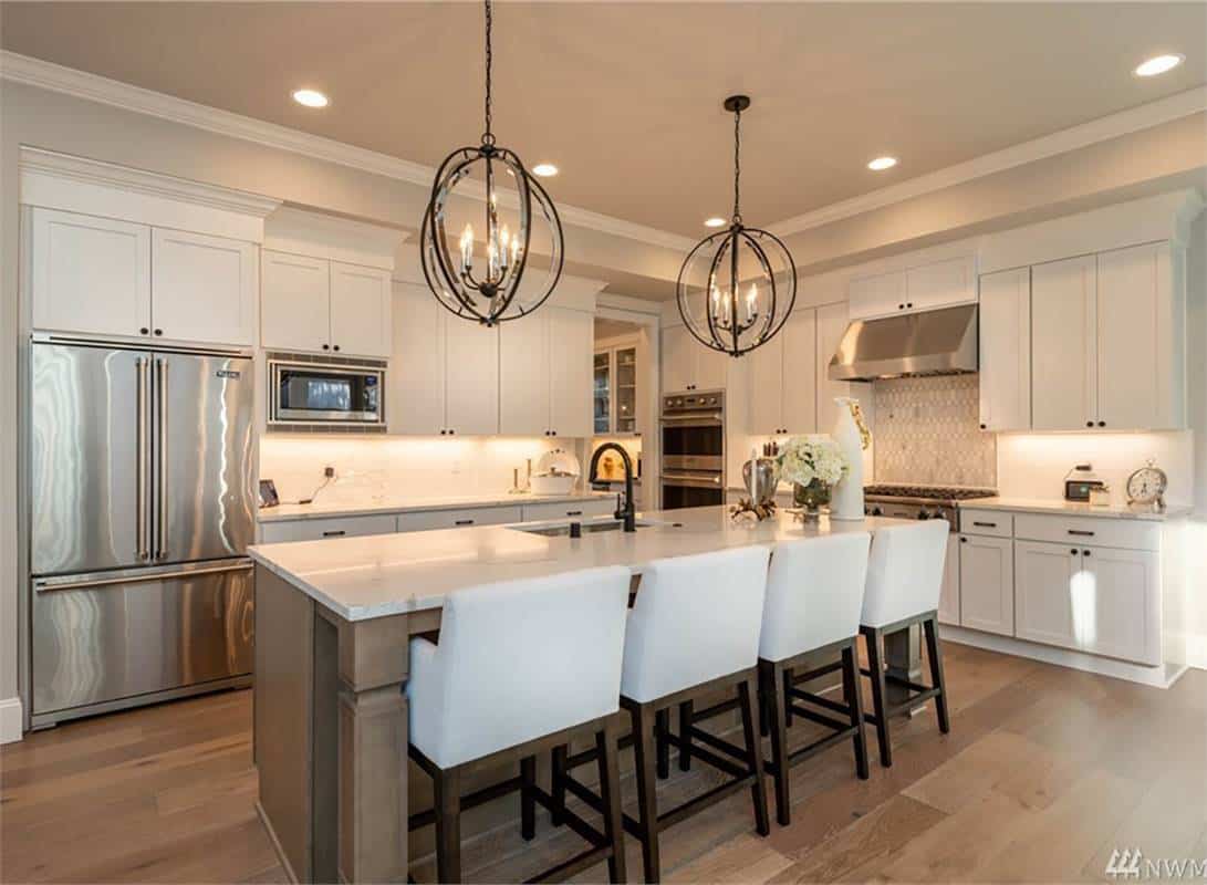 Kitchen with stainless steel appliances, white cabinets, and a breakfast island with four seating.