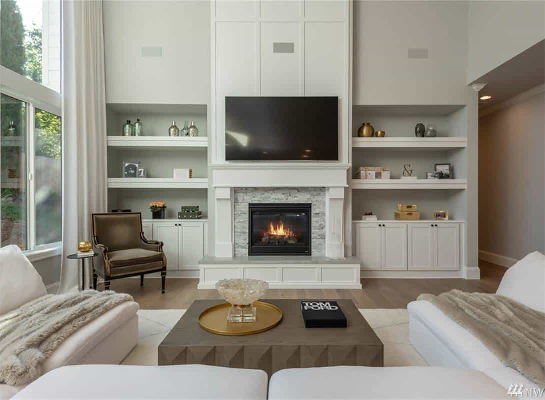 Great room with neutral seats, a wall-mounted TV, and a fireplace flanked by white built-ins.