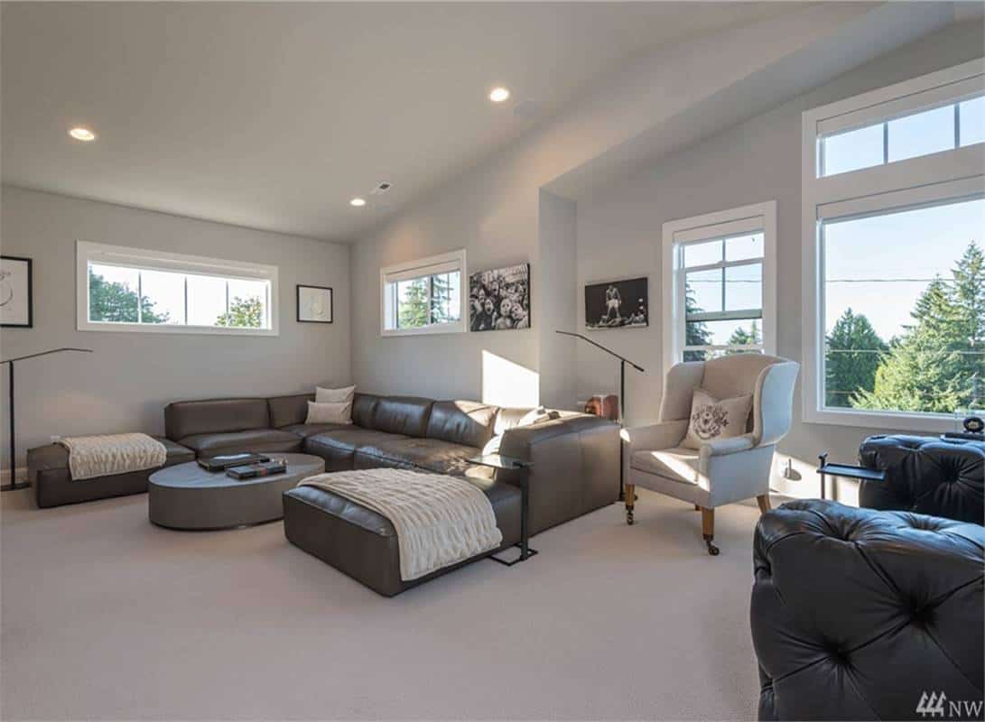 Media room with leather sofas, a wingback armchair, and a round coffee table over the carpeted floor.