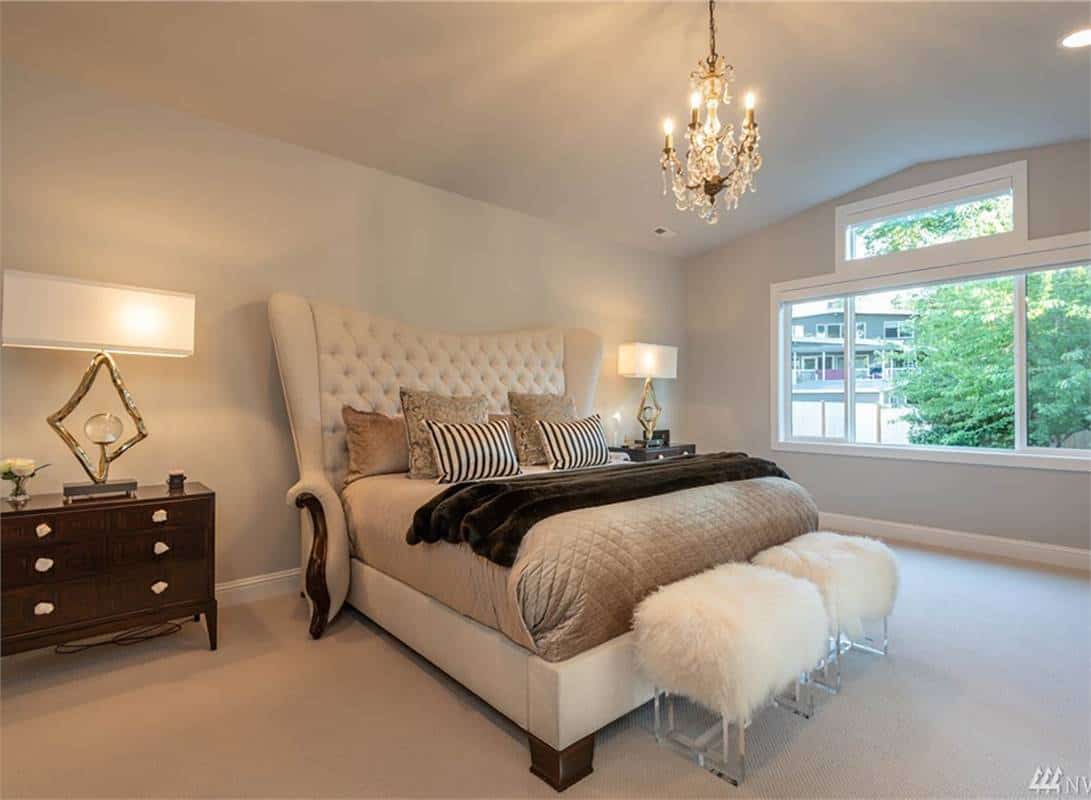 Primary bedroom with a vaulted ceiling and a tufted wingback bed complemented with a couple of furry stools.