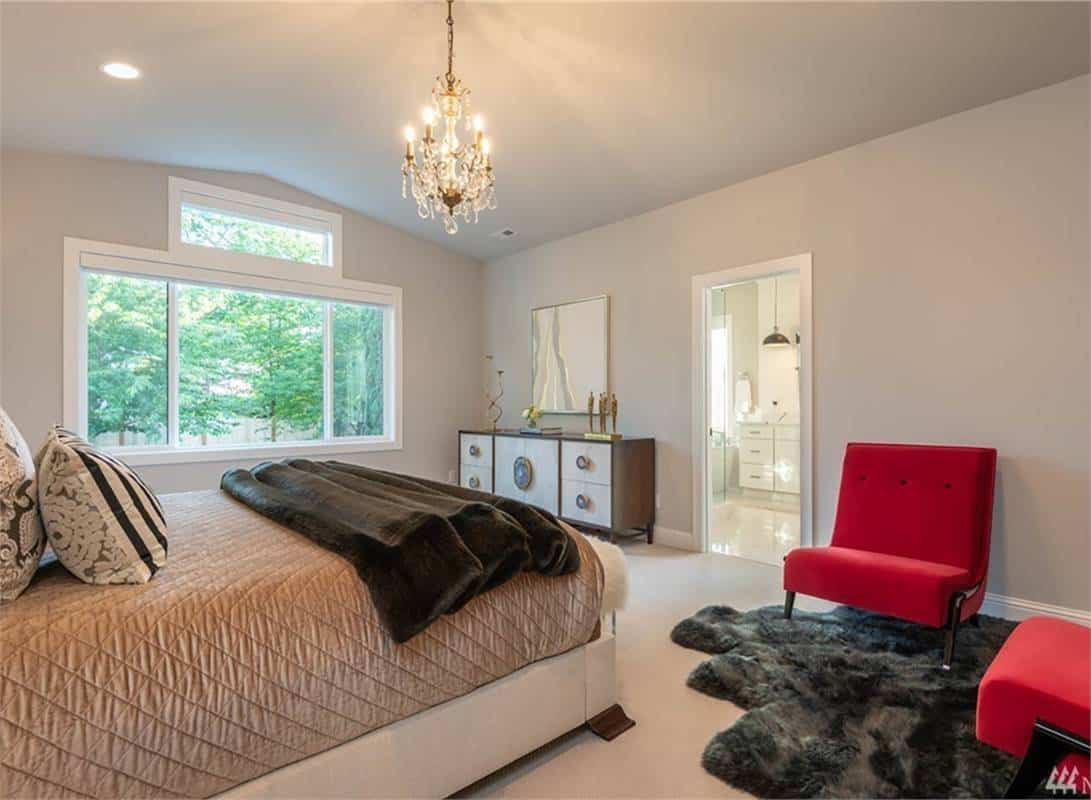 The primary bedroom includes red modern chairs, a wooden vanity, and an ensuite bathroom.