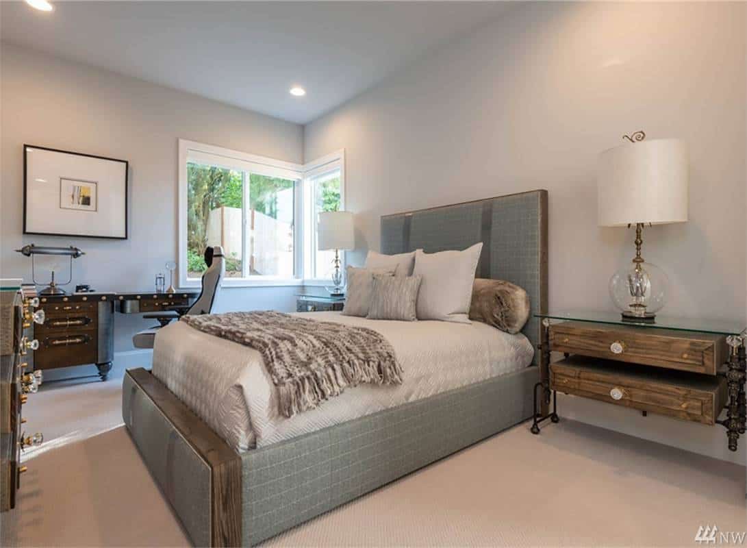 Secondary bedroom with wooden furnishings and corner windows that invite natural light in.