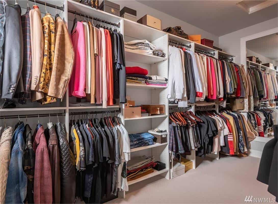 Primary walk-in closet with white built-ins and a full-length mirror.