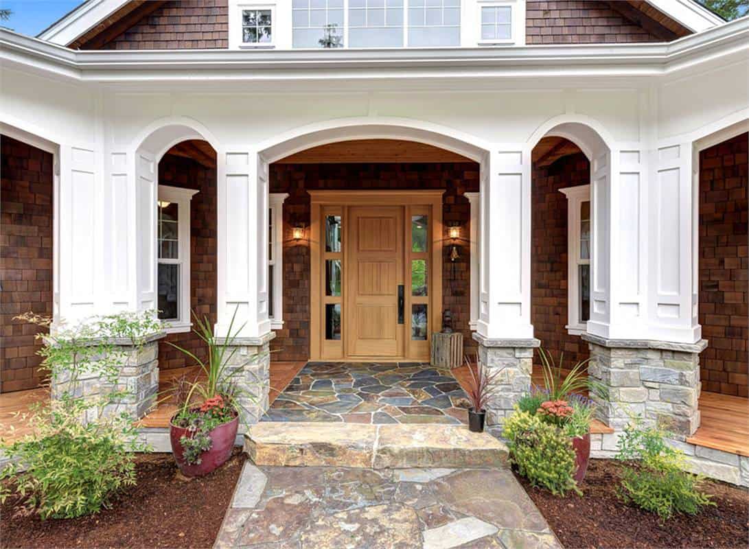 Entry porch with stone base columns, decorative arches, and a wooden front door.