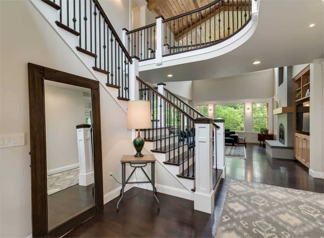 Foyer with full-length mirror, a patterned rug, and a traditional staircase.