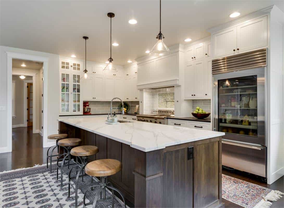 Kitchen with white cabinetry, marble countertops, and a breakfast island with four seating.