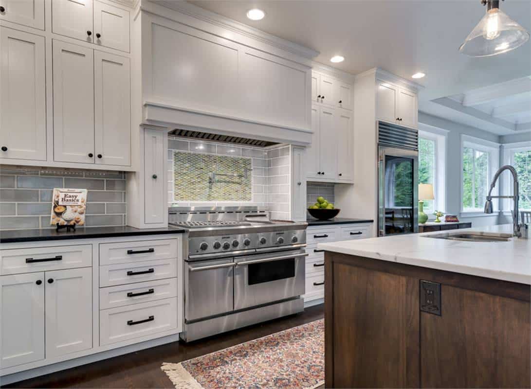 The kitchen includes a fridge and a stainless steel cooking range with subway tiled backsplash.