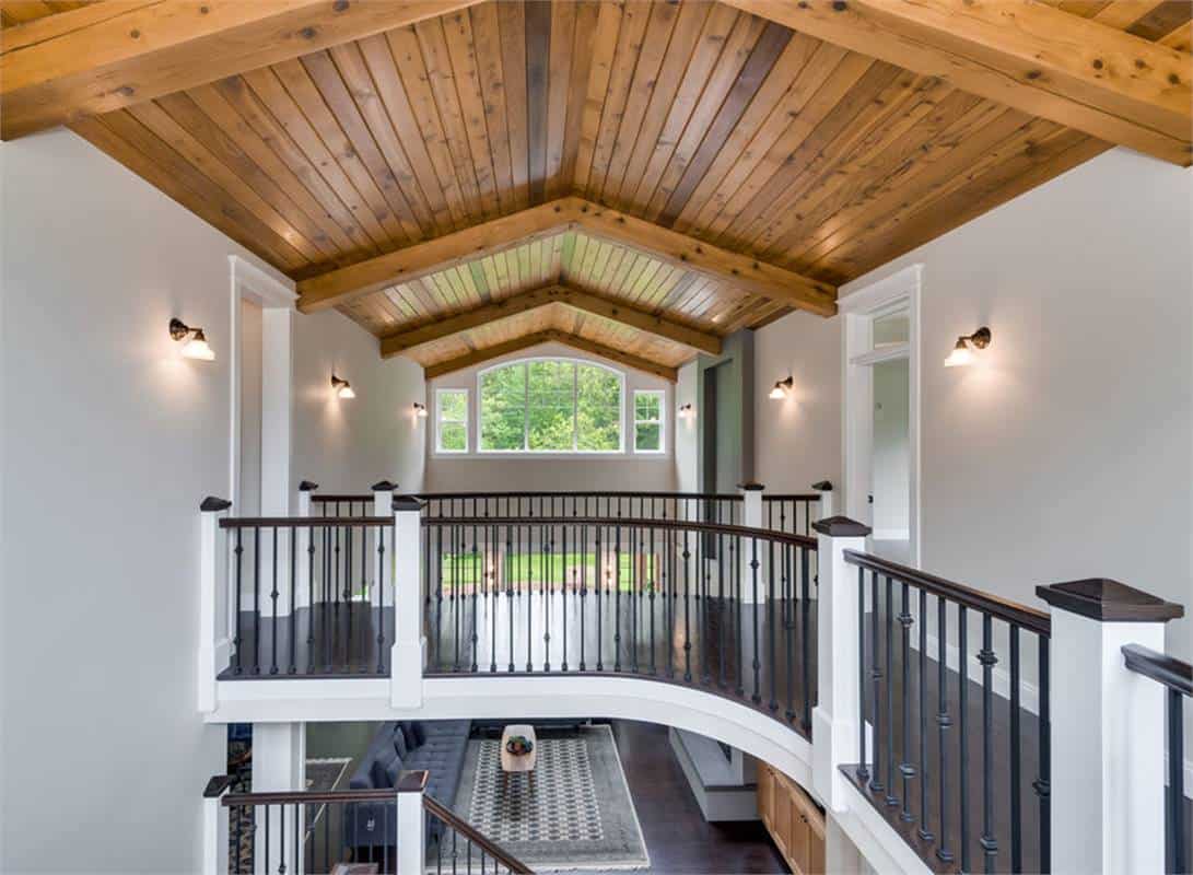 Balcony bridge under a wood-paneled ceiling leading to the secondary bedrooms.